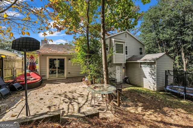 rear view of house featuring a patio area, a storage unit, and a trampoline