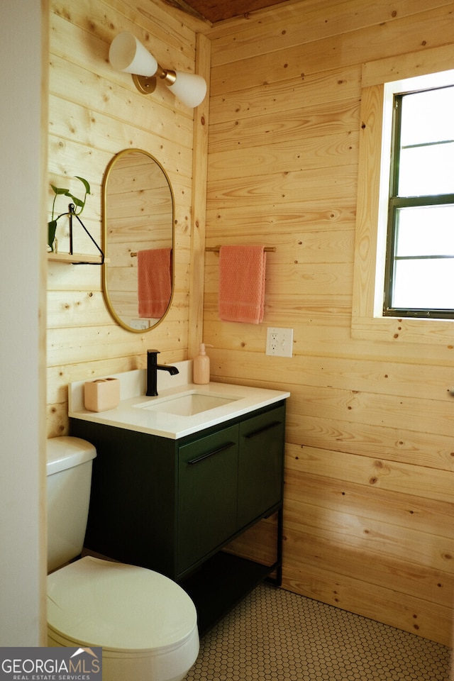 bathroom featuring vanity, toilet, and wooden walls