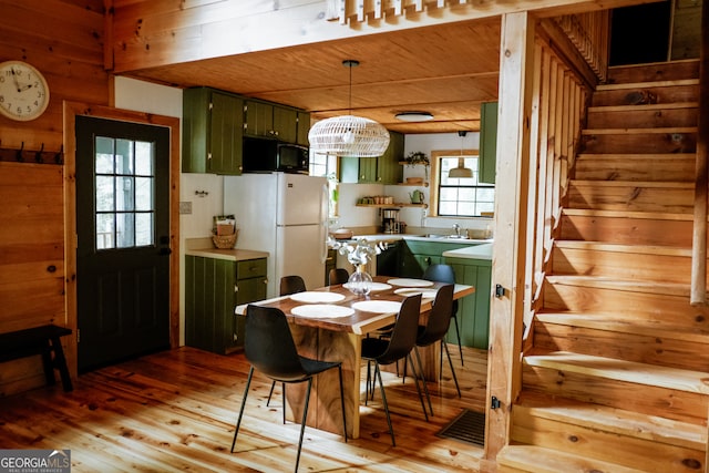 dining room featuring wooden walls, light hardwood / wood-style flooring, wood ceiling, and a healthy amount of sunlight