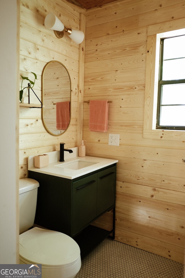 bathroom with vanity, wooden walls, and toilet