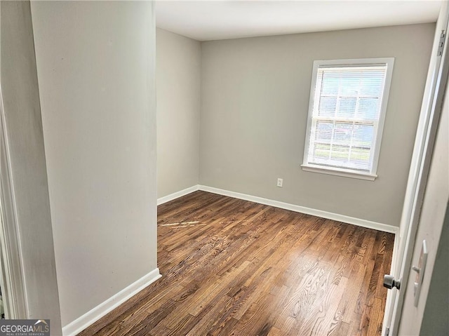 empty room featuring dark wood-style floors and baseboards