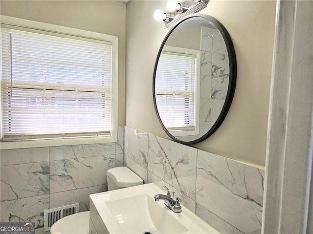 half bathroom featuring toilet, plenty of natural light, vanity, and visible vents