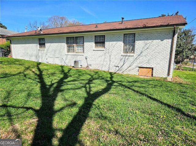 back of house featuring central AC unit, crawl space, fence, a yard, and brick siding