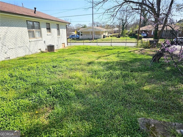 view of yard with central AC and fence