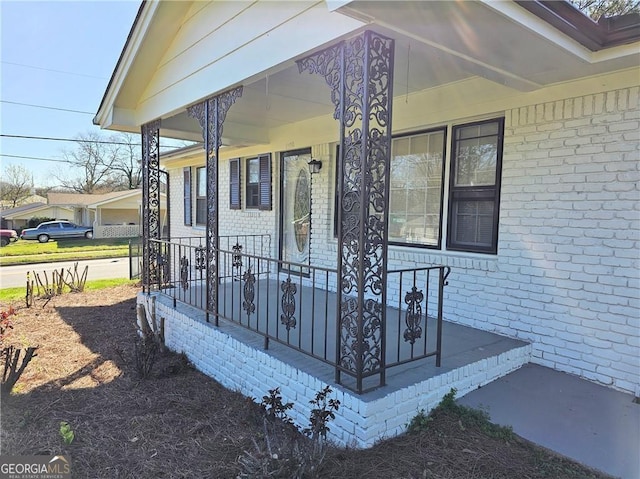 property entrance featuring covered porch and brick siding