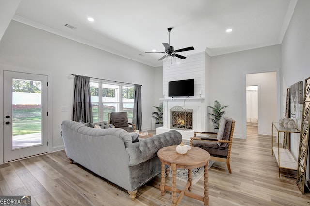 living room with ceiling fan, light hardwood / wood-style flooring, a wealth of natural light, and a fireplace