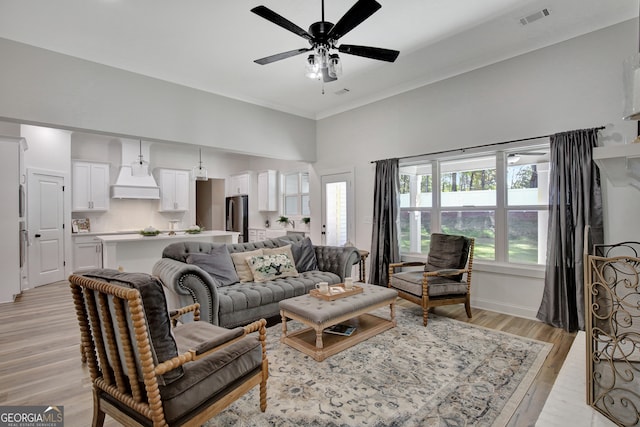 living room with a wealth of natural light, light hardwood / wood-style flooring, and ceiling fan