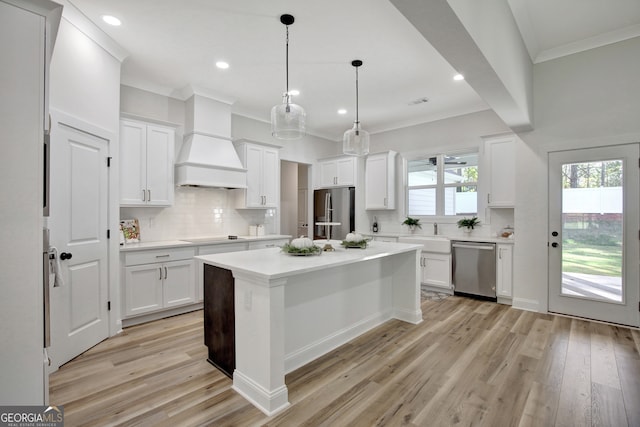 kitchen with appliances with stainless steel finishes, decorative light fixtures, light hardwood / wood-style floors, and white cabinets