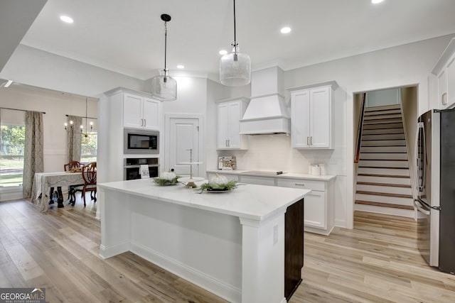 kitchen featuring a center island, pendant lighting, white cabinetry, appliances with stainless steel finishes, and light hardwood / wood-style floors