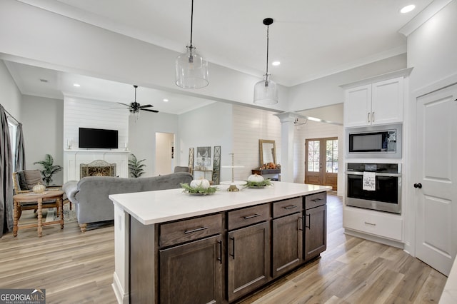 kitchen featuring dark brown cabinets, white cabinets, decorative light fixtures, appliances with stainless steel finishes, and a fireplace