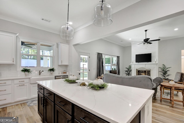 kitchen with white cabinetry, a large fireplace, light wood-type flooring, and backsplash