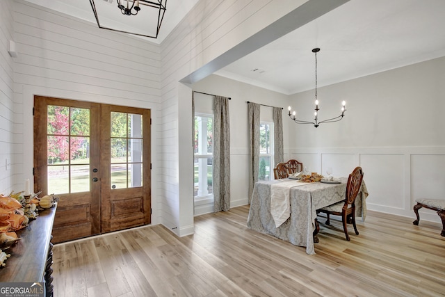 dining space with ornamental molding, french doors, a notable chandelier, and light wood-type flooring