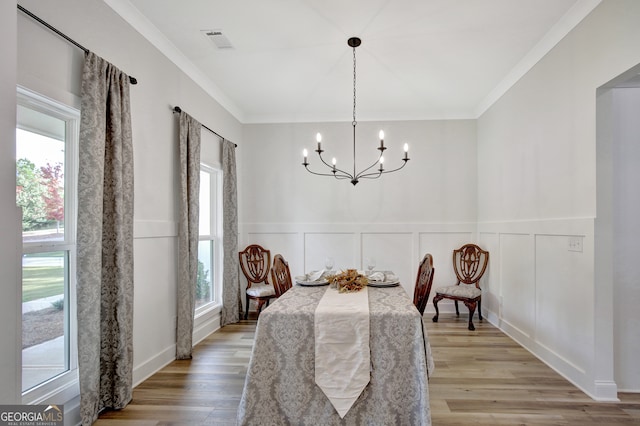 dining room with crown molding, hardwood / wood-style floors, and a notable chandelier