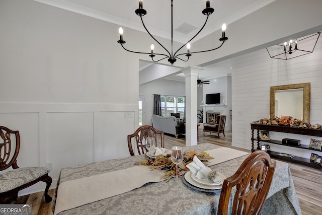 dining area with light hardwood / wood-style flooring, ceiling fan with notable chandelier, and ornate columns