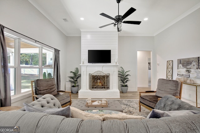 living room featuring hardwood / wood-style flooring, a healthy amount of sunlight, crown molding, and a fireplace