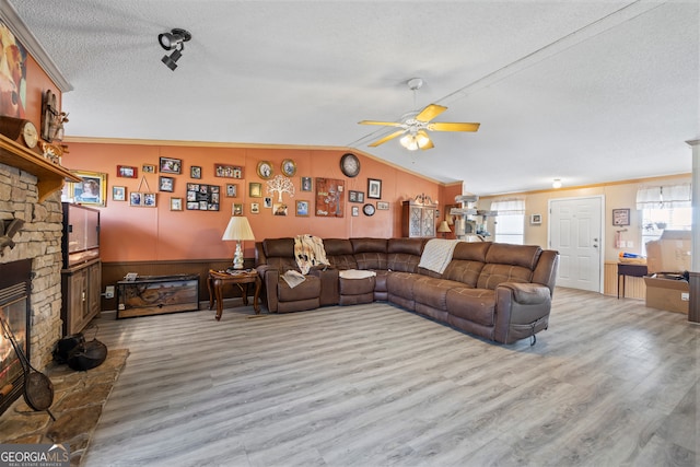 living room with ceiling fan, lofted ceiling, a textured ceiling, and light hardwood / wood-style floors