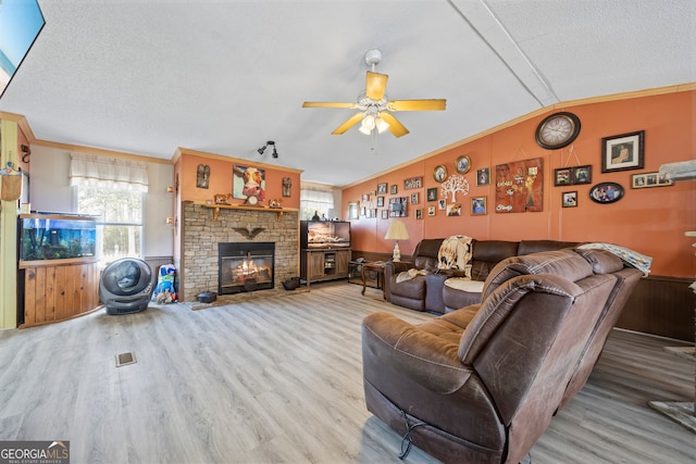 living room with a fireplace, hardwood / wood-style flooring, lofted ceiling, and ornamental molding