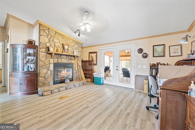 office area featuring light hardwood / wood-style floors, ceiling fan, a textured ceiling, a fireplace, and french doors