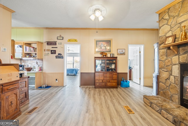 living room with a textured ceiling, light hardwood / wood-style flooring, ceiling fan, and crown molding