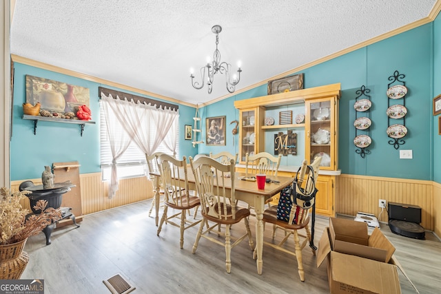 dining room featuring light hardwood / wood-style floors, a chandelier, a textured ceiling, and crown molding