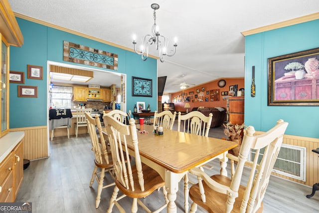 dining space with ornamental molding, ceiling fan with notable chandelier, light hardwood / wood-style flooring, and lofted ceiling