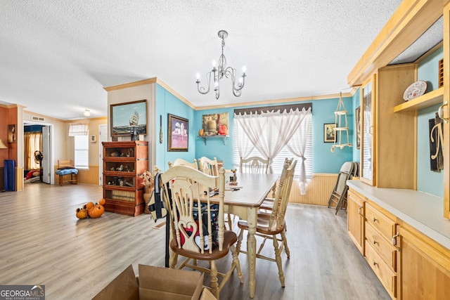 dining room featuring ornamental molding, light hardwood / wood-style floors, a textured ceiling, and a healthy amount of sunlight