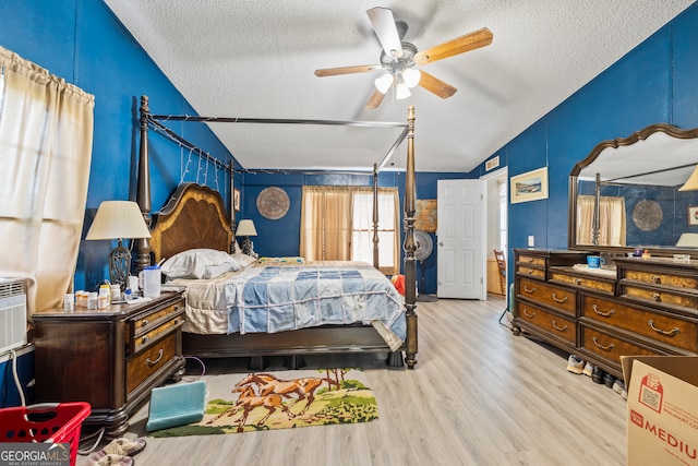 bedroom with light hardwood / wood-style flooring, a textured ceiling, ceiling fan, and vaulted ceiling