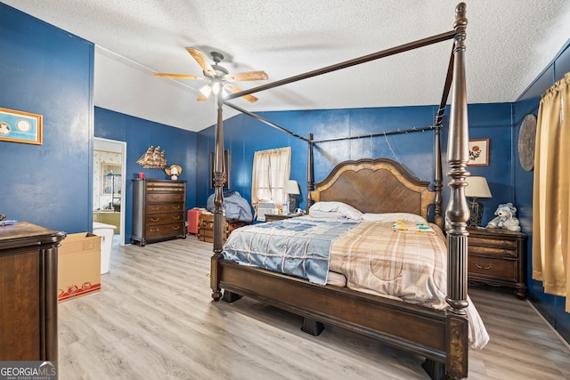 bedroom with light wood-type flooring, lofted ceiling, a textured ceiling, and ceiling fan