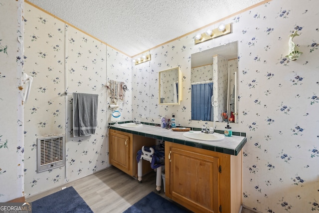 bathroom featuring heating unit, vanity, a textured ceiling, and hardwood / wood-style flooring