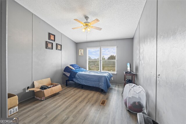 bedroom featuring ceiling fan, a textured ceiling, and wood-type flooring