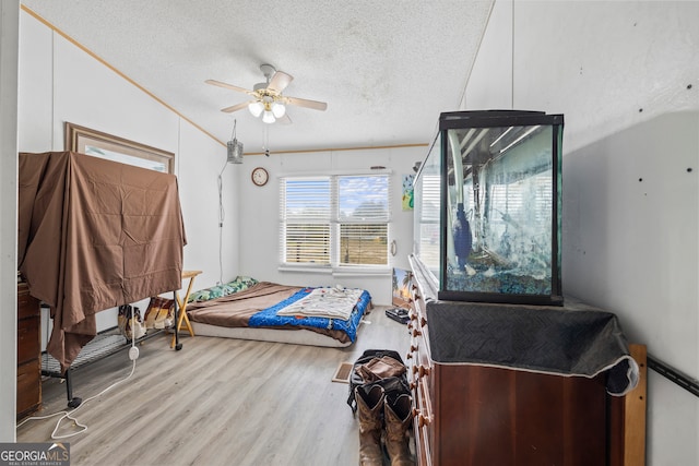 bedroom with ceiling fan, a textured ceiling, light hardwood / wood-style flooring, and lofted ceiling