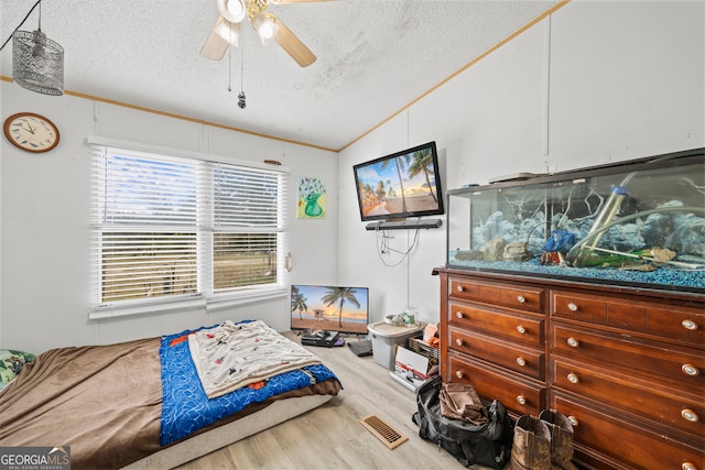 bedroom featuring ceiling fan, a textured ceiling, light hardwood / wood-style floors, and crown molding