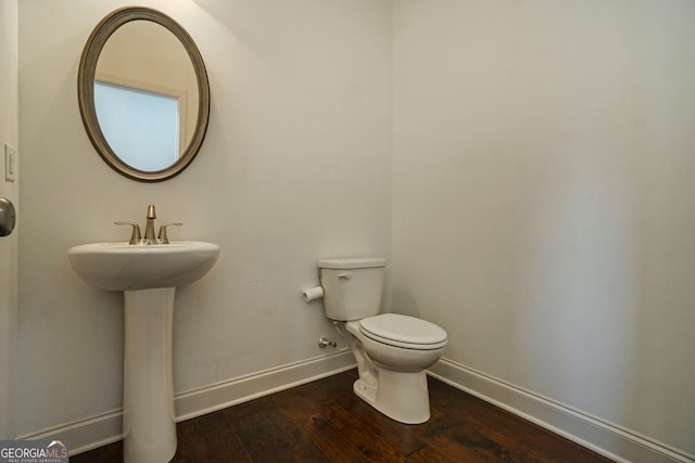 bathroom with toilet, sink, and wood-type flooring