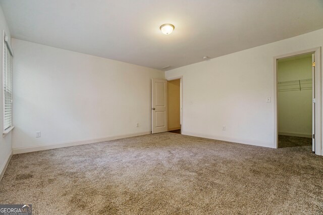 unfurnished bedroom featuring a walk in closet, a closet, and carpet flooring