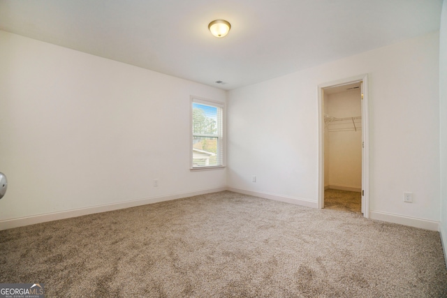 unfurnished bedroom featuring a walk in closet, a closet, and carpet floors