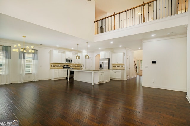 unfurnished living room featuring an inviting chandelier, crown molding, dark hardwood / wood-style floors, and a high ceiling