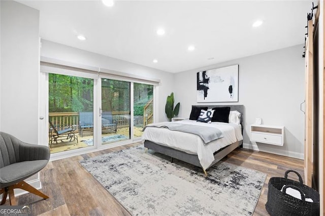 bedroom with a barn door, access to exterior, and hardwood / wood-style floors