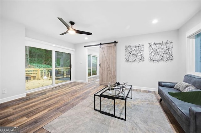 living room with hardwood / wood-style floors, a barn door, and ceiling fan