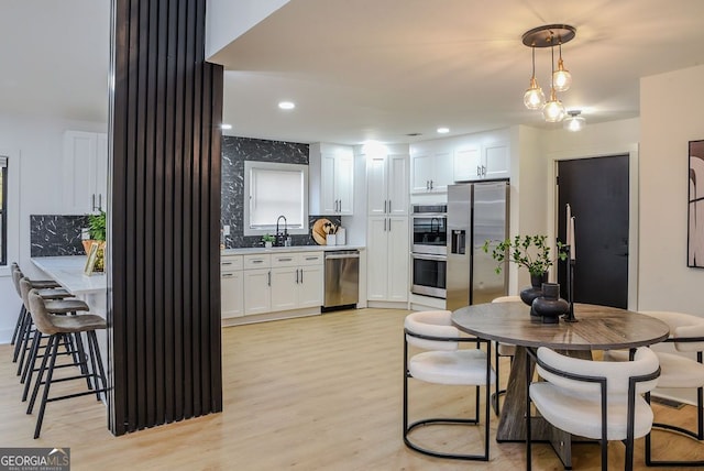 kitchen with pendant lighting, backsplash, stainless steel appliances, and white cabinetry