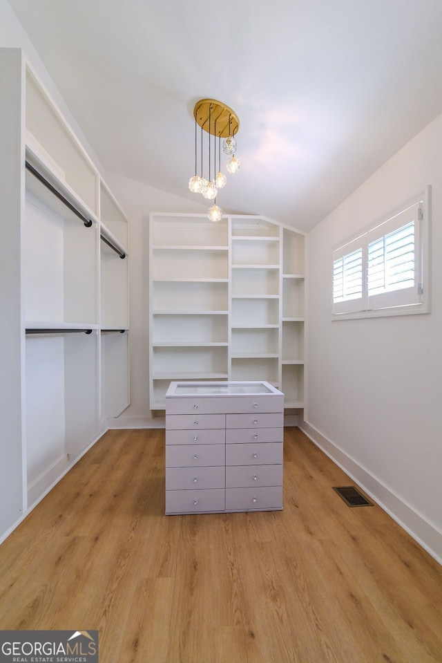 spacious closet featuring lofted ceiling and light wood-type flooring