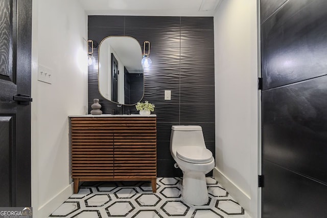 bathroom featuring tile patterned flooring, vanity, toilet, and tile walls