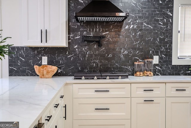 kitchen featuring light stone countertops, backsplash, gas stovetop, and wall chimney exhaust hood