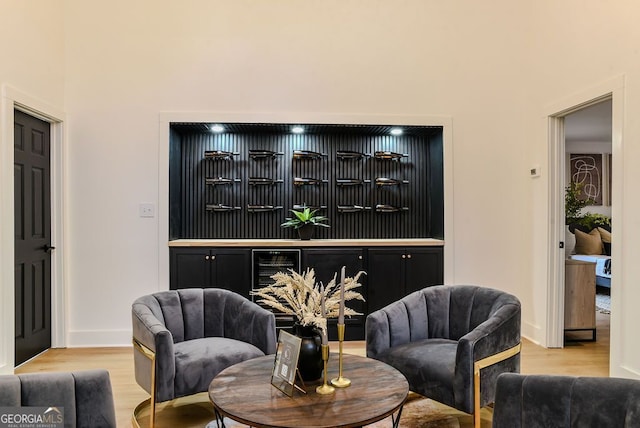 living area with light wood-type flooring, wine cooler, and indoor bar