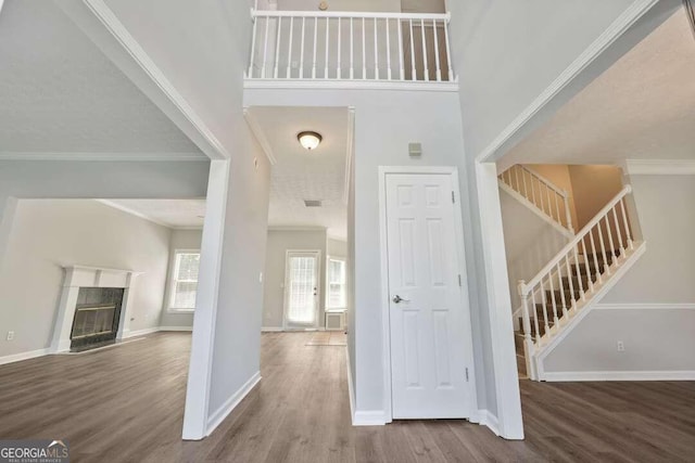 entrance foyer featuring a high ceiling, wood-type flooring, ornamental molding, and a high end fireplace