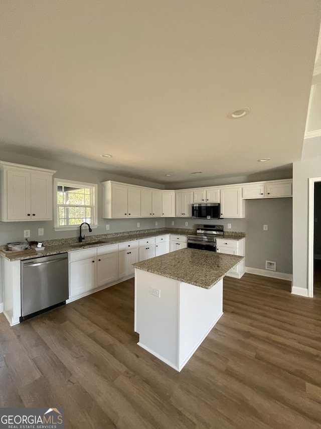 kitchen with white cabinets, appliances with stainless steel finishes, dark hardwood / wood-style floors, sink, and a center island