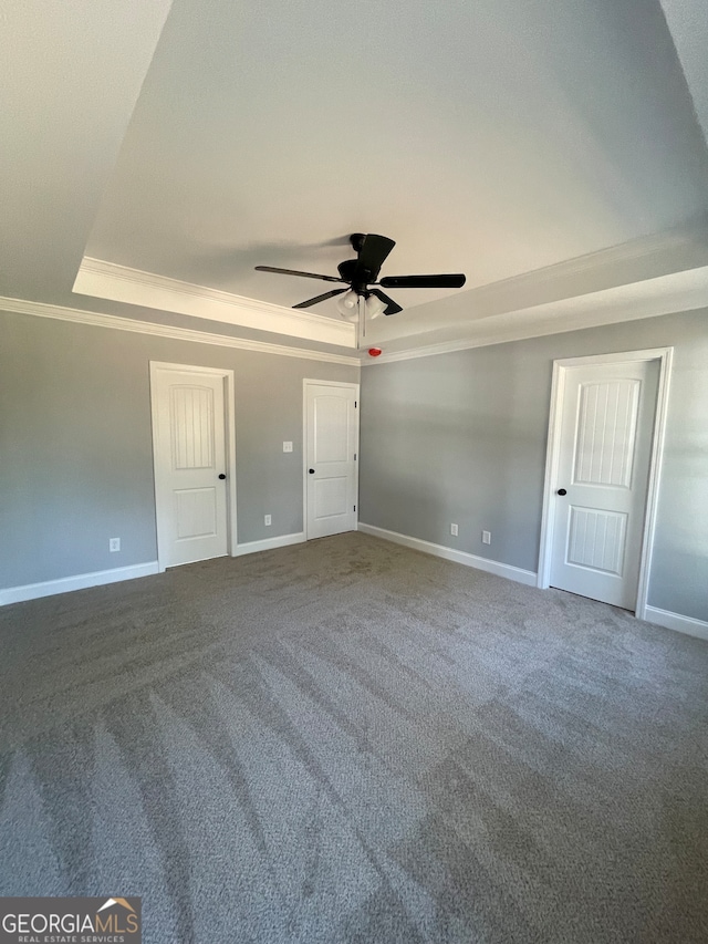 carpeted empty room with ornamental molding, a tray ceiling, and ceiling fan