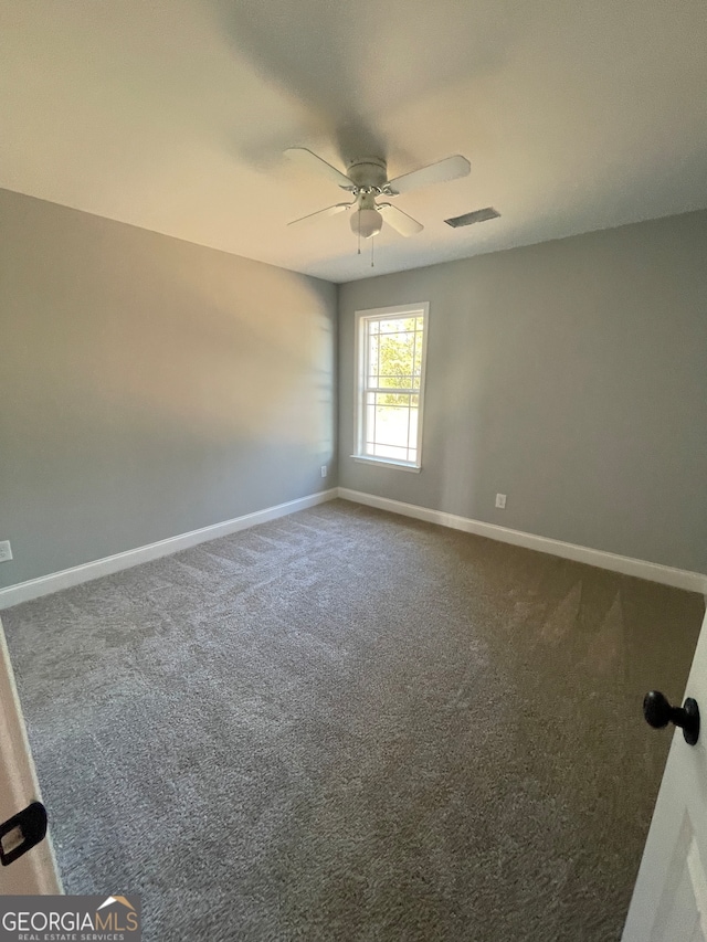 spare room with ceiling fan and dark carpet