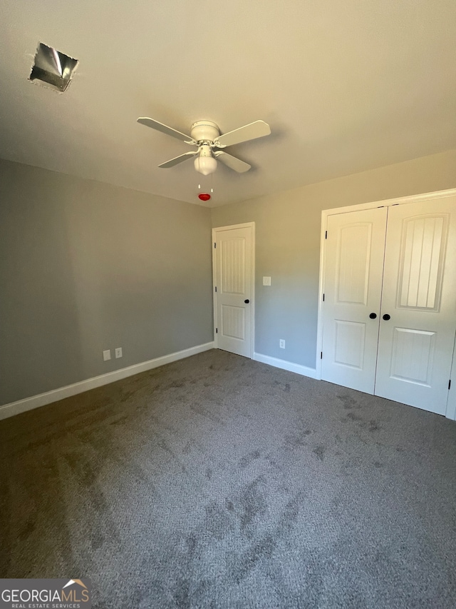 unfurnished bedroom with a closet, dark carpet, and ceiling fan