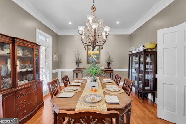 dining space featuring light wood-type flooring, crown molding, and a chandelier