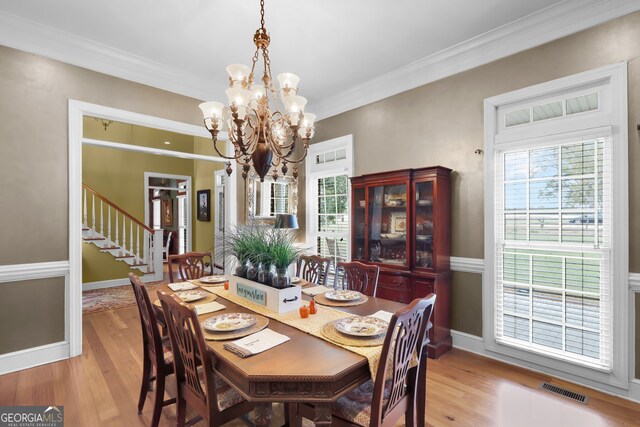 dining area with crown molding, light hardwood / wood-style flooring, and a notable chandelier